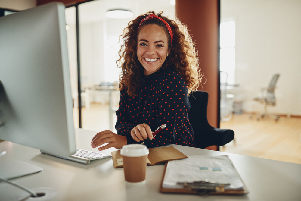 Smiling young businesswoman working at her compute